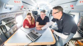 Three researchers view content on a laptop in the test lab.