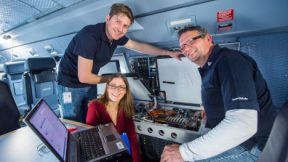 Three researchers with technical equipment in the test lab.