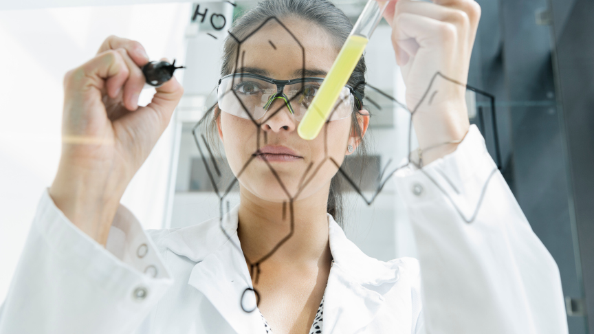 Medical student draws atoms on a glass wall in the lab.