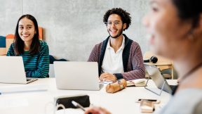 Internationale Studierende sitzen mit Laptops am Tische bei einem Seminar an der Universität.