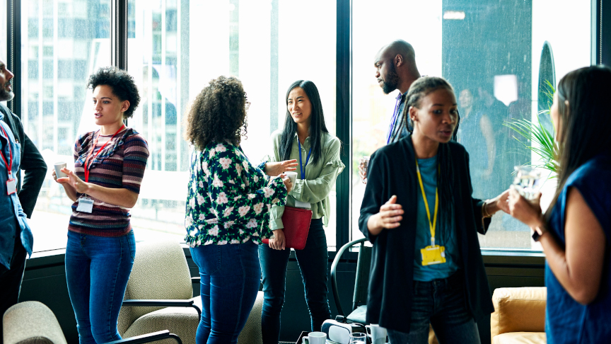 International alumni stand together in groups at an event and talk.